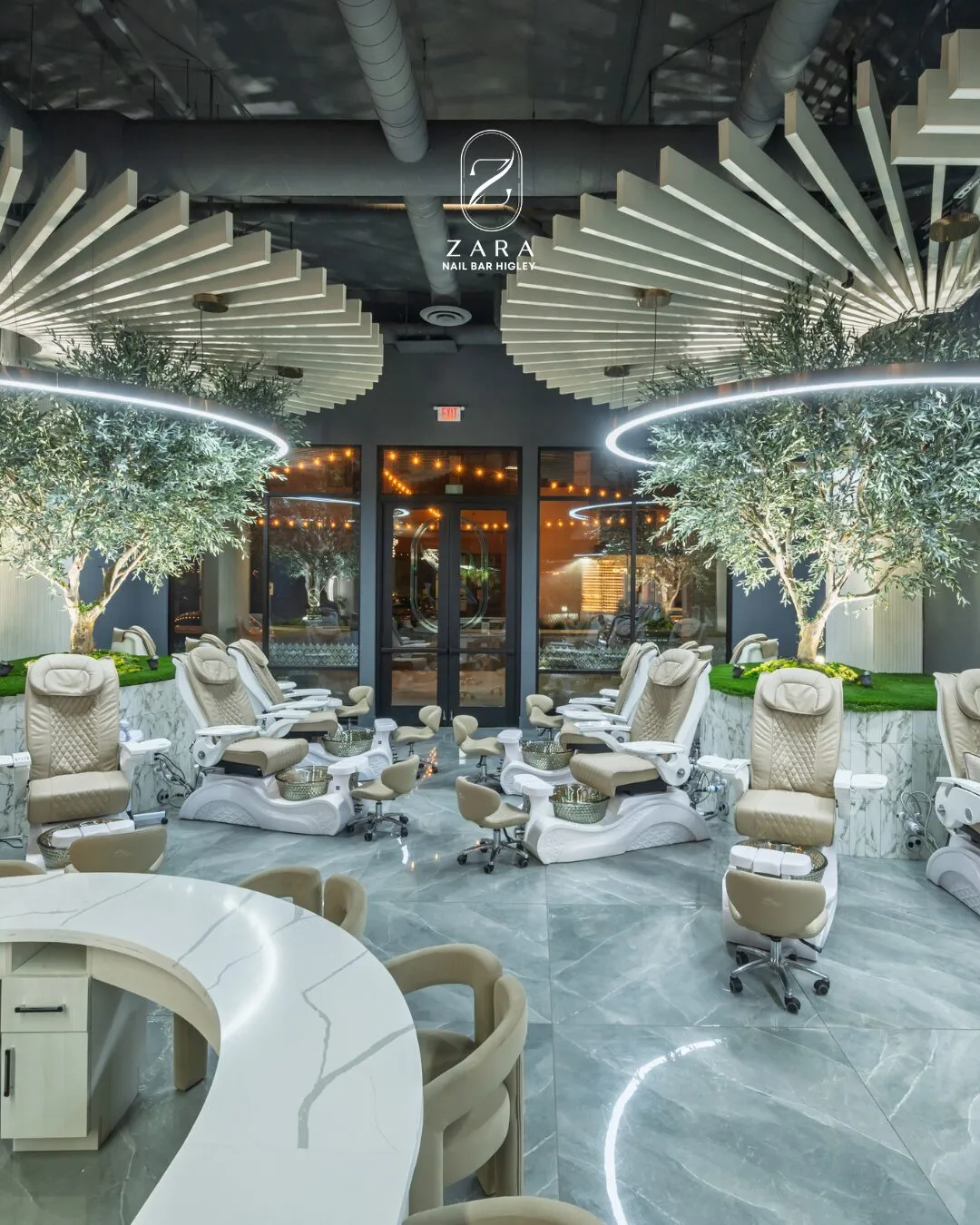 Cream pedicure chairs beneath olive trees and a ribbed ceiling at Zara Nail Bar Higley, with the Zara sign above the glass entrance.