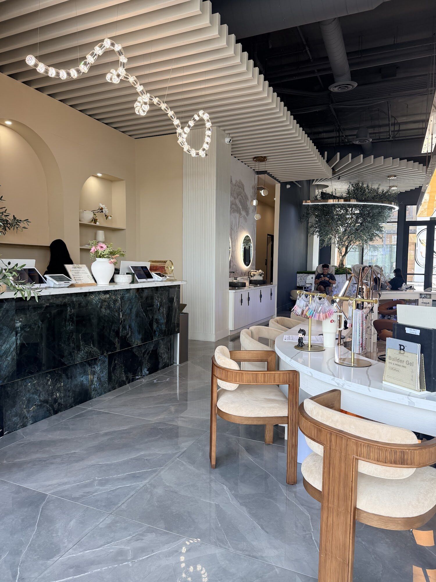The front desk at Zara Nail Bar Higley: green marble, arched shelves and woven chairs at the curved manicure bar beneath a slatted ceiling.