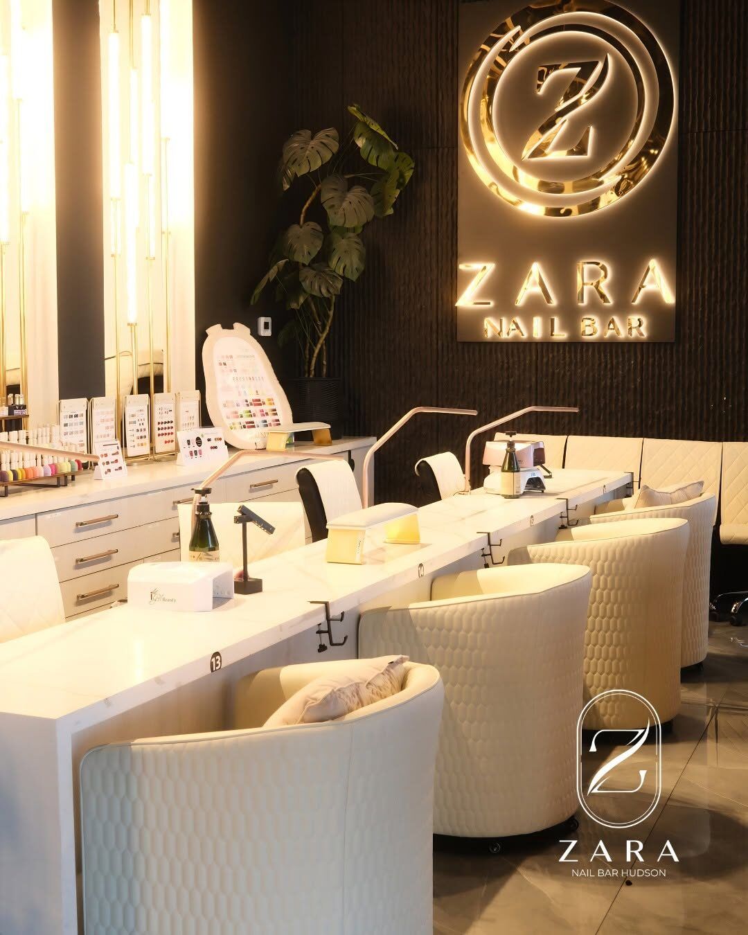 Cream manicure stations with quilted chairs beneath the lit Zara Nail Bar sign at Zara Nail Bar Hudson.