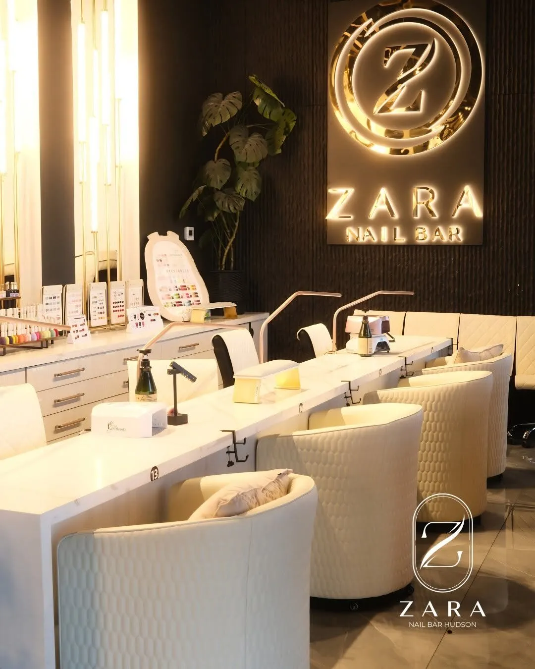 Cream manicure stations with quilted chairs beneath the lit Zara Nail Bar sign at Zara Nail Bar Hudson.