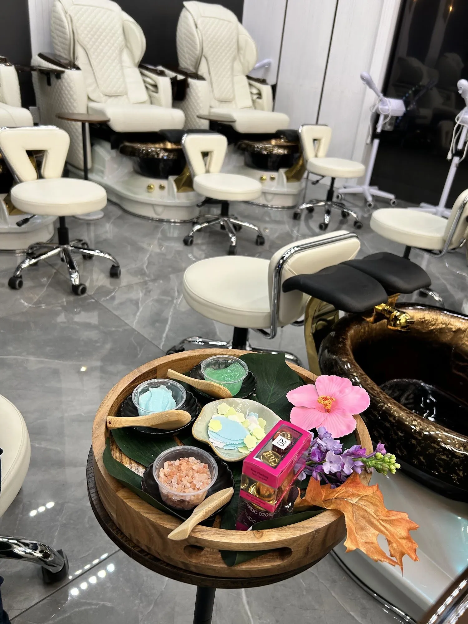 A pedicure tray at Zara Nail Bar Hudson with bowls of pink salt and scrub, a hibiscus flower and a gold pedicure bowl.